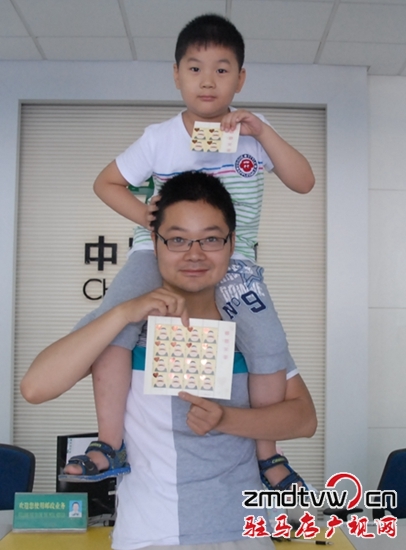 图为6月13日，一对父子在市中心邮政所展示“感恩父亲”特种邮票 .JPG